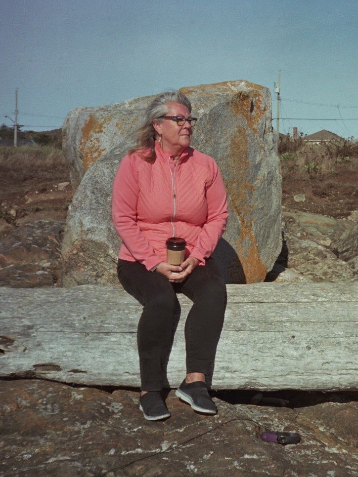 Woman in pink jacket by boulder