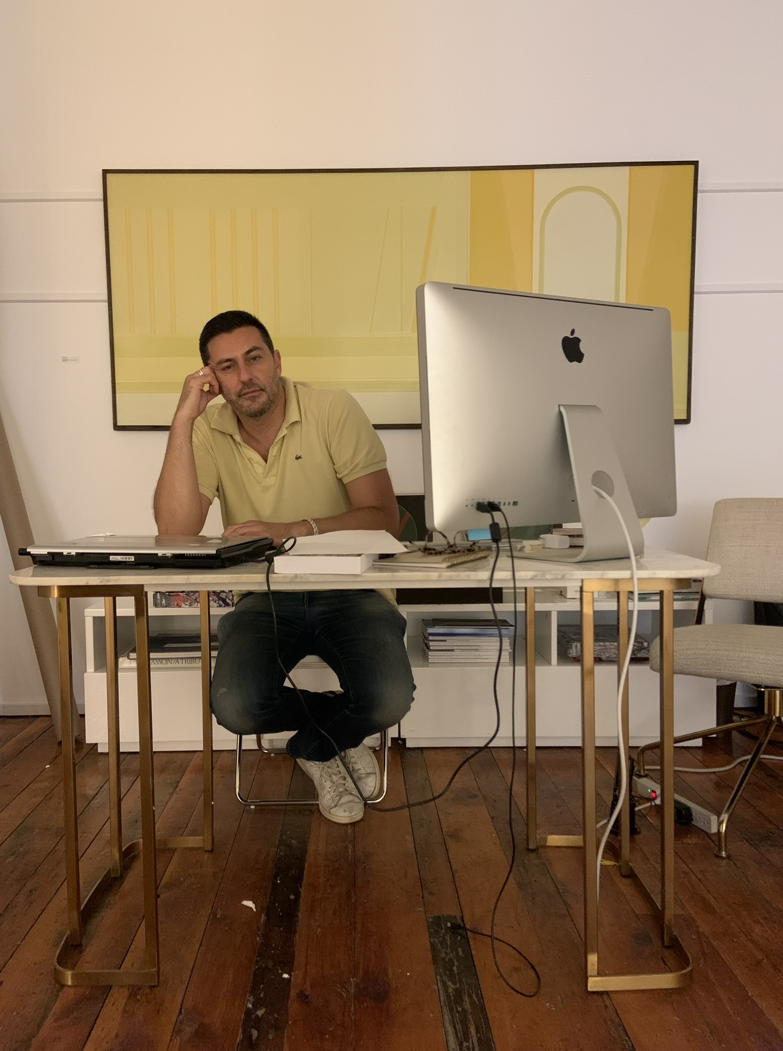 Man at desk with iMac and yellow painting