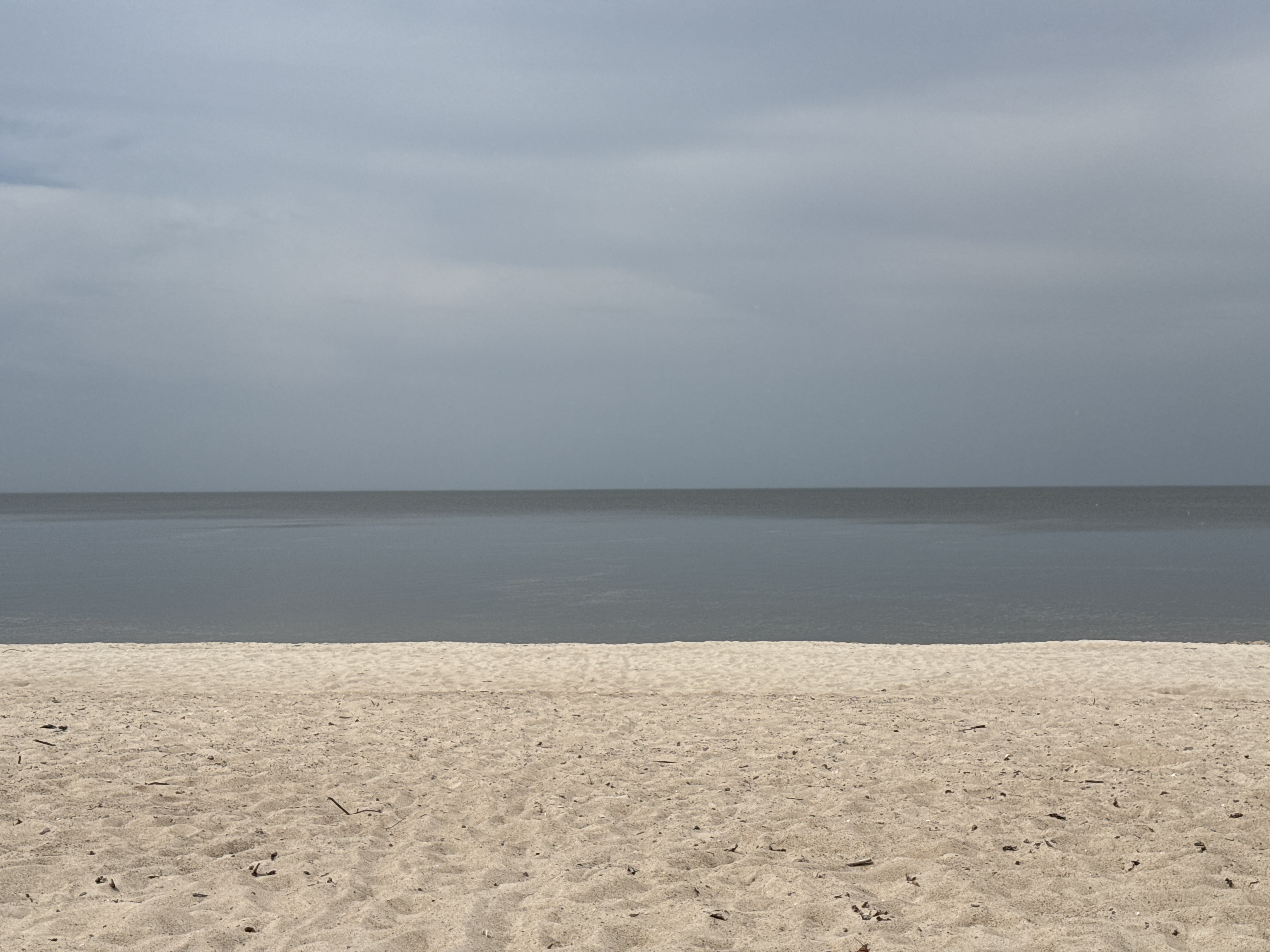 Grey lake horizon and white sand